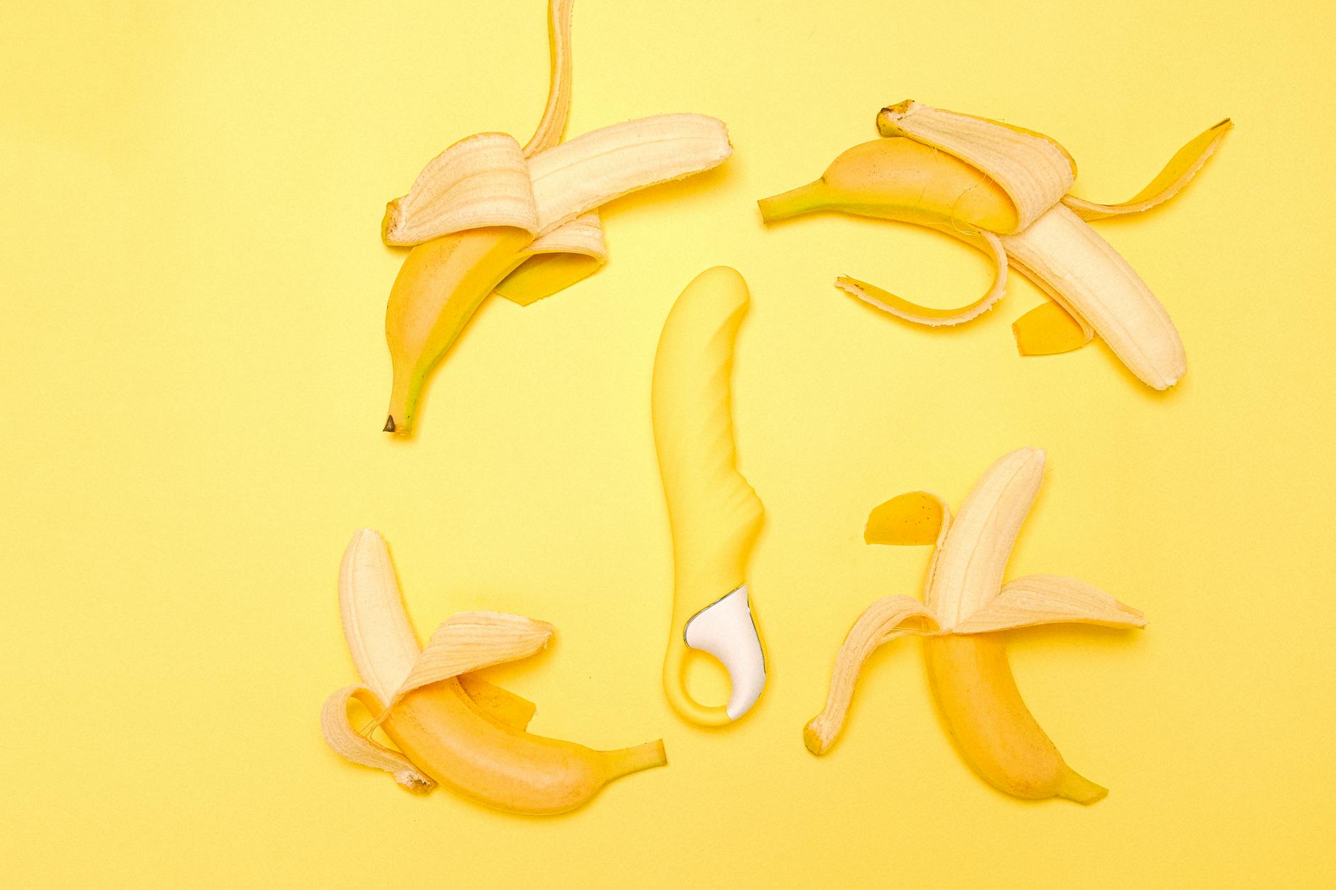 Bright yellow lemon vibrator surrounded by fresh lemon slices on a vibrant yellow background