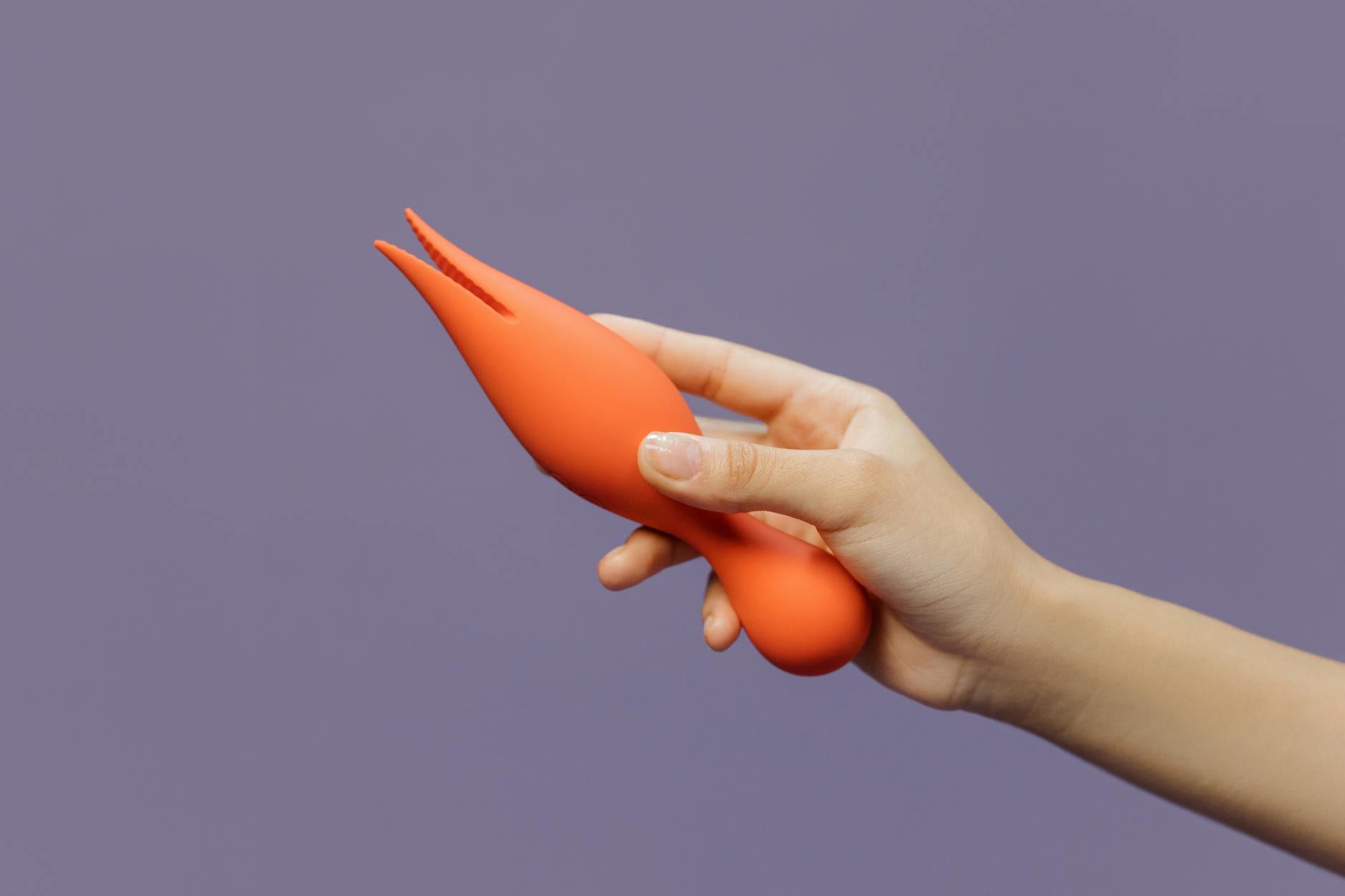 Mão segurando um vibrador de limão contra um fundo minimalista roxo, mostrando sensualidade moderna