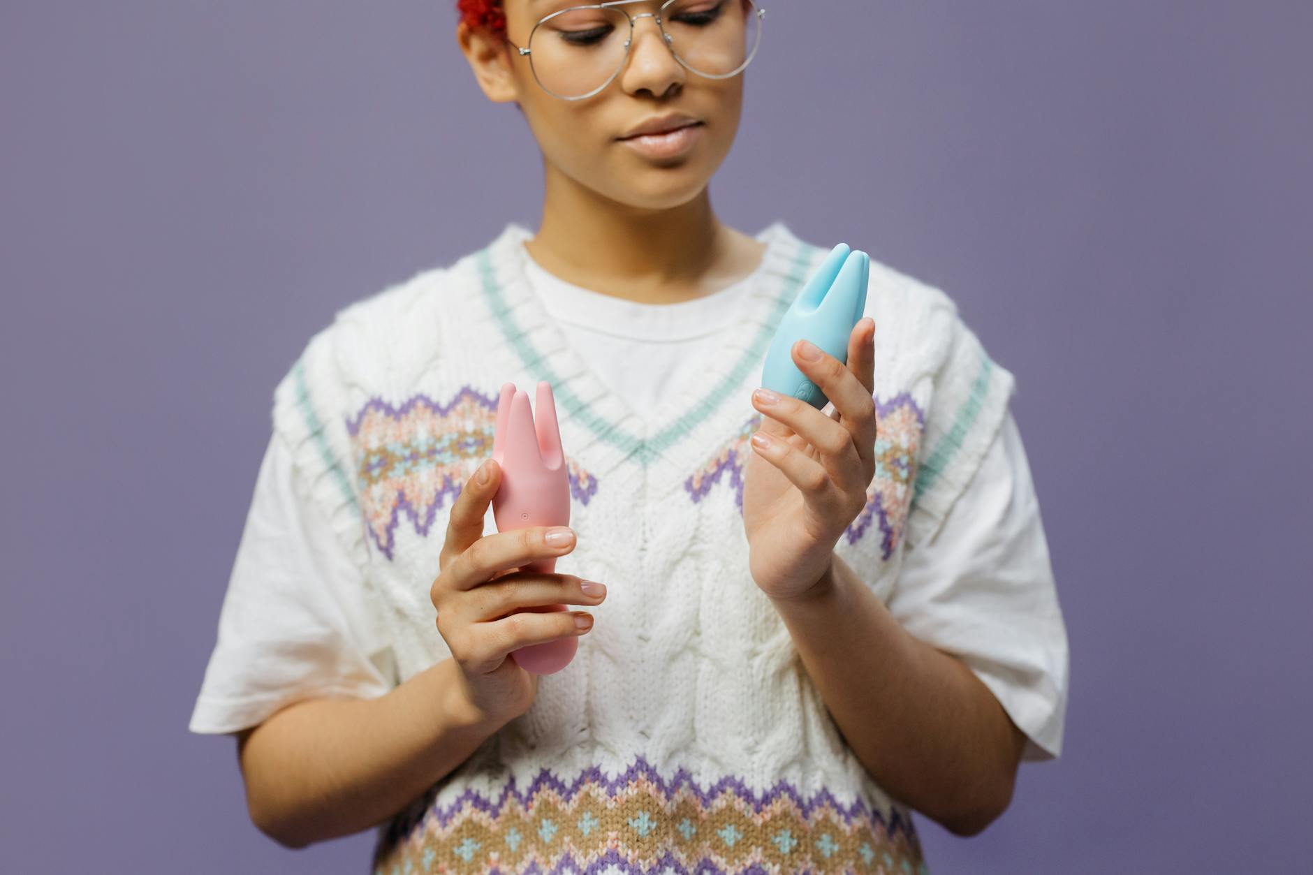 Woman holding blue and pink vibrators with intention and care, representing trauma-informed pleasure