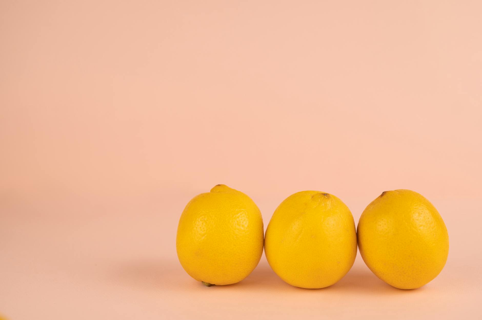 Mão segurando vibrador laranja contra fundo roxo minimalista